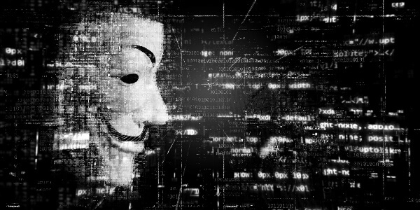 a guy fawkes mask representing cyber criminals is surrounded by data and internet imagery, representing the threat against cyber security