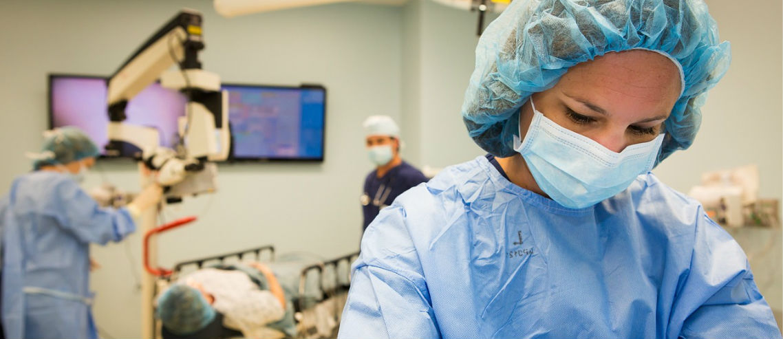 a doctor examines her tools in the foreground whilst a patient lies on an operating table in the background, symbolizing the need for surgical insurance in Singapore