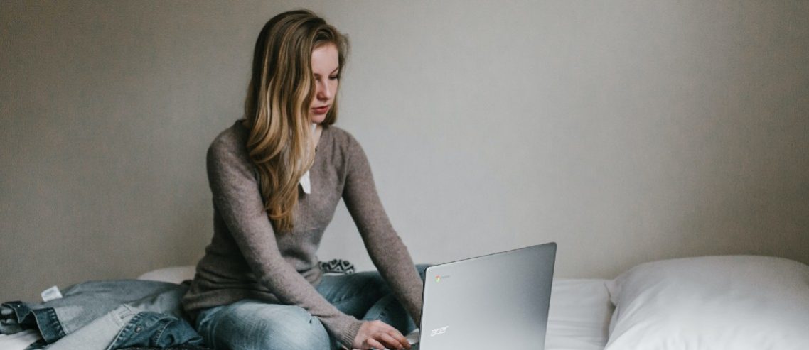 Woman on the bed working on her laptop from home