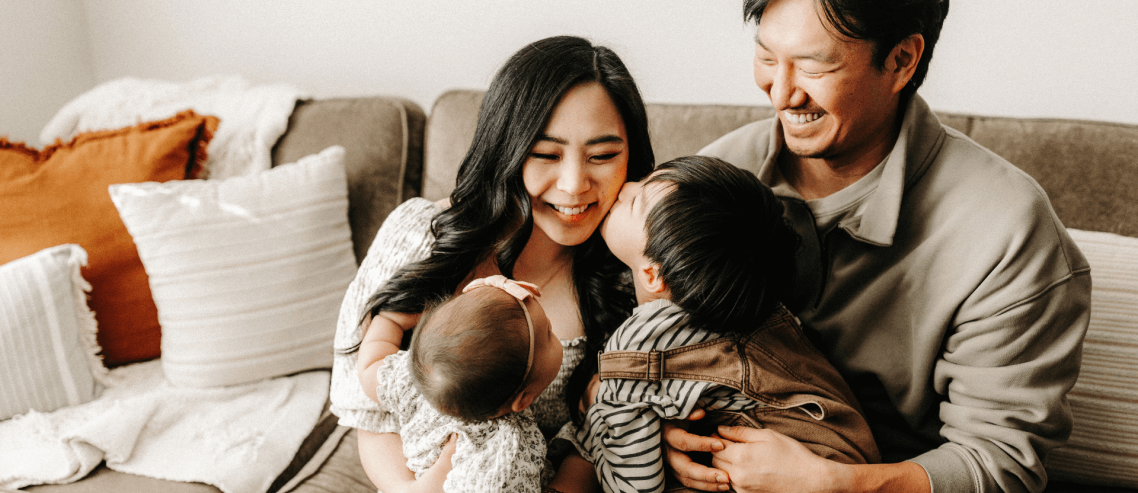 healthy family of four holding each other looking happy